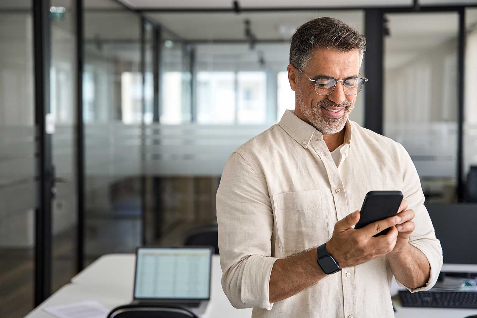 CEO smiling at his phone after seeing seamless payroll administration