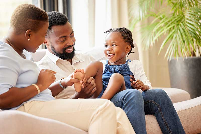 Mother and father on couch with their daughter