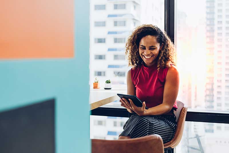 Smiling woman looking at tablet in her office