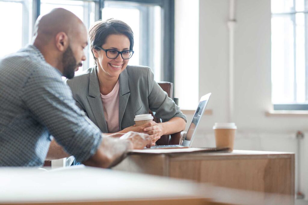 Two financial consultants reviewing data on a computer together