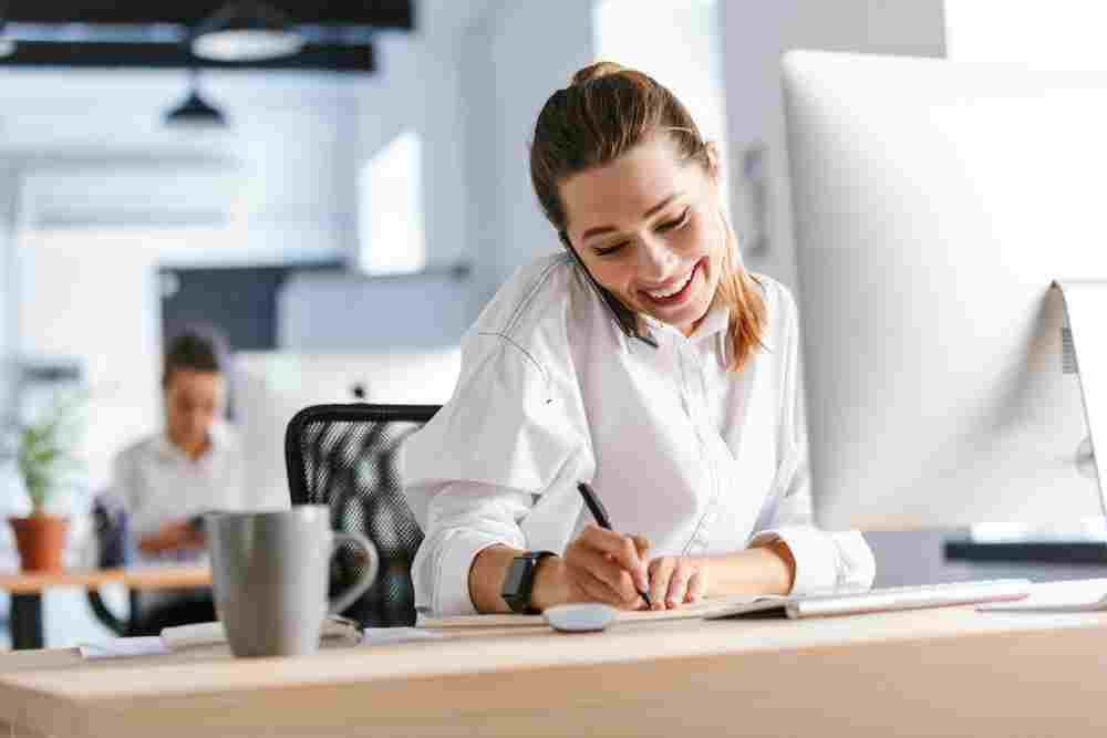 Cheerful young businesswoman sitting at her workplace