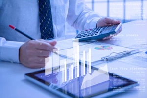 analyst holding calculator while reviewing financial statements for business performance or cash flow analysis