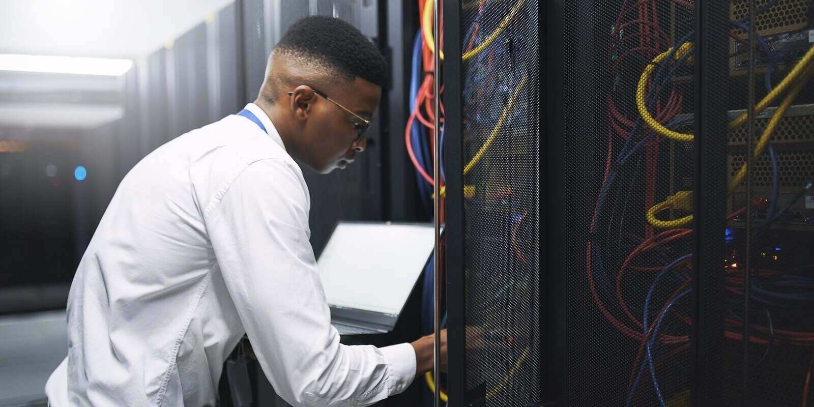 technician and server room with laptop screen for network repair or hardware fault at data center